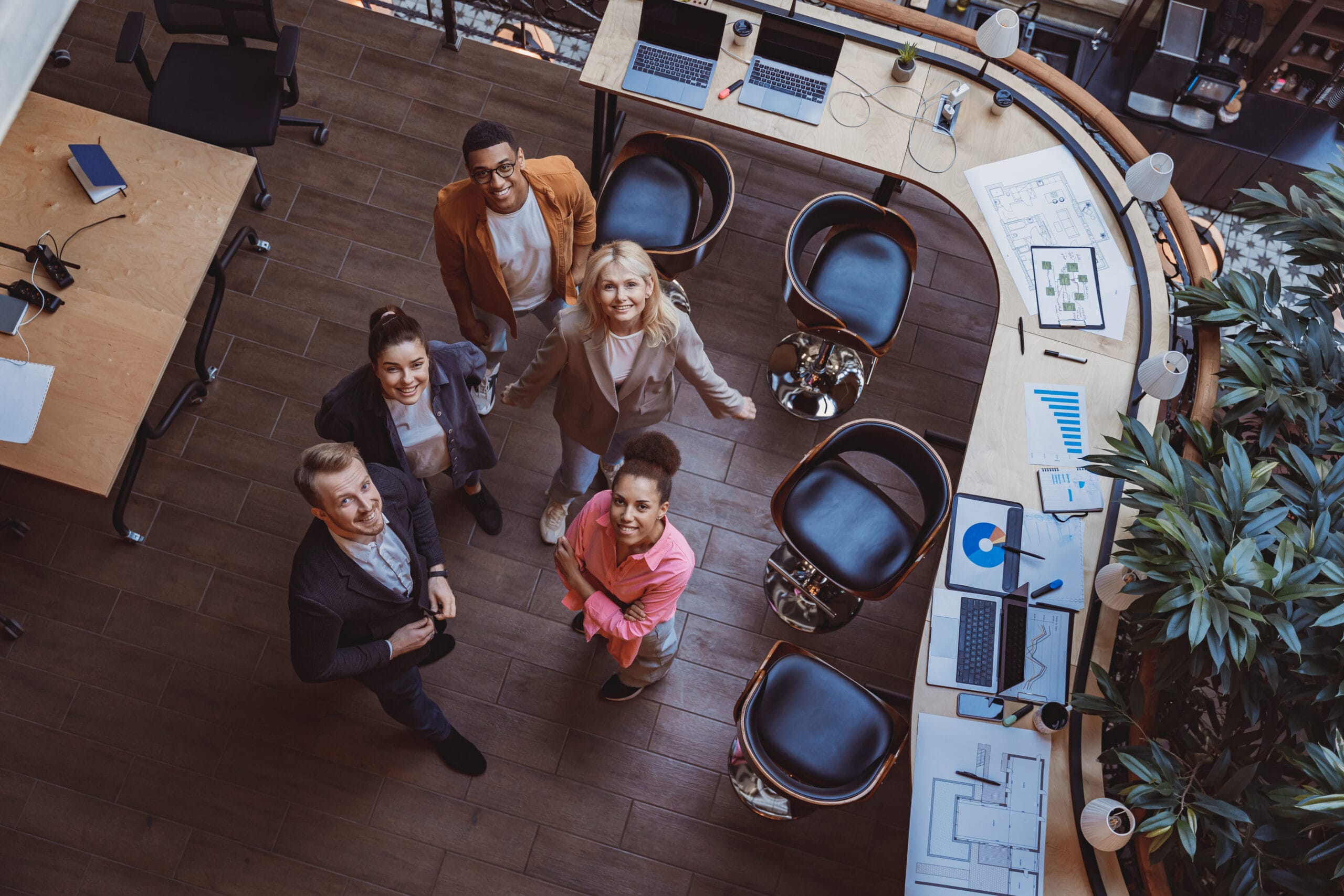 Group of coworkers standing at office and looking up at camera. Workplace and cooperation concept Group of coworkers standing at office and looking up at camera. Workplace and cooperation concept
