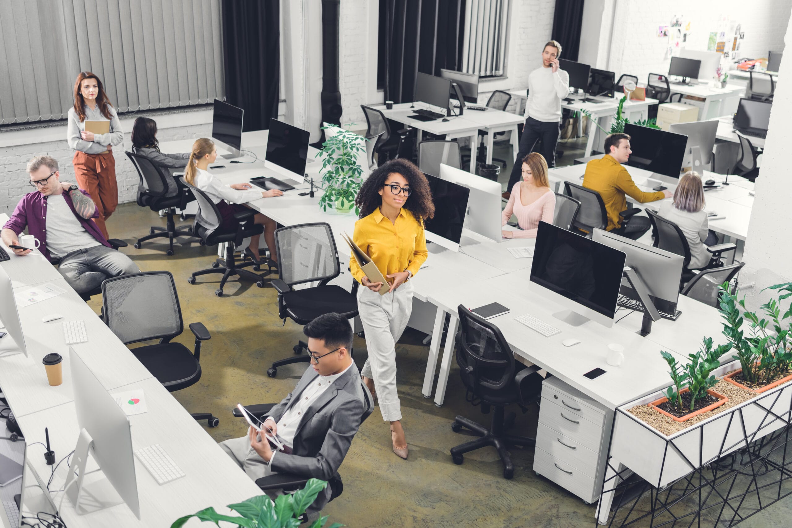 high angle view of multiracial young businesspeople working with computers and documents in open high angle view of multiracial young businesspeople working with computers and documents in open